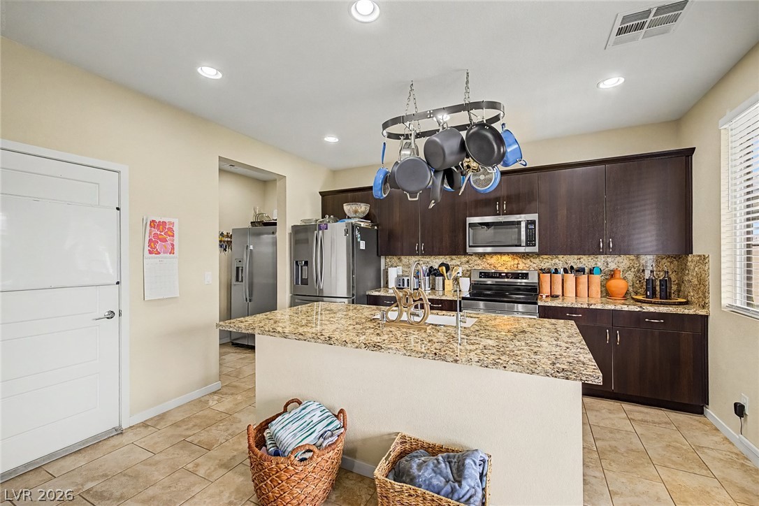 4914 East Beacon Ridge Drive Pahrump, NV 89061 - Photo 13 of 34 A well-appointed kitchen showcasing a spacious island with a sink and rich wood cabinetry, perfect for culinary endeavors.