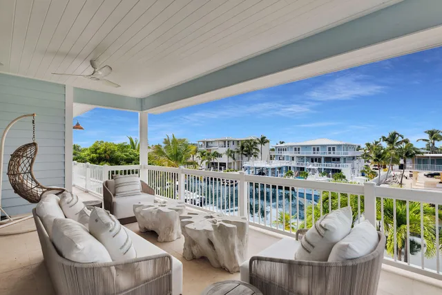 a view of a patio with couches chairs potted plants and wooden fence