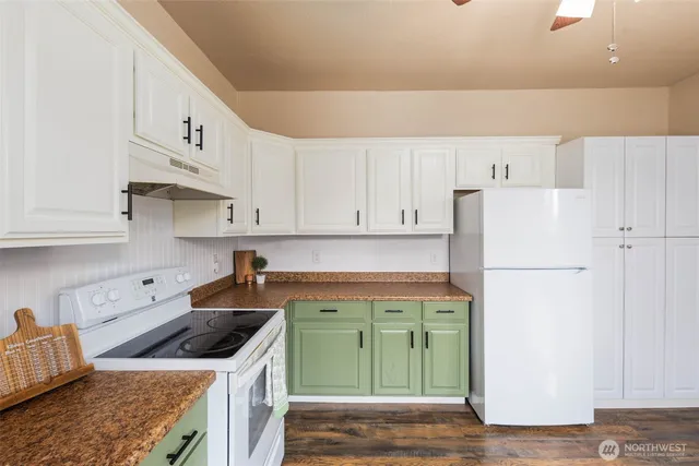 a kitchen with a refrigerator a stove a sink and white cabinets with wooden floor
