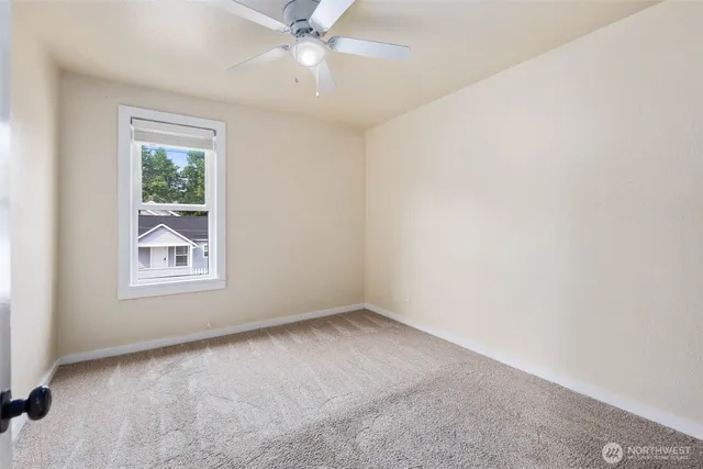an empty room with a window and a fan