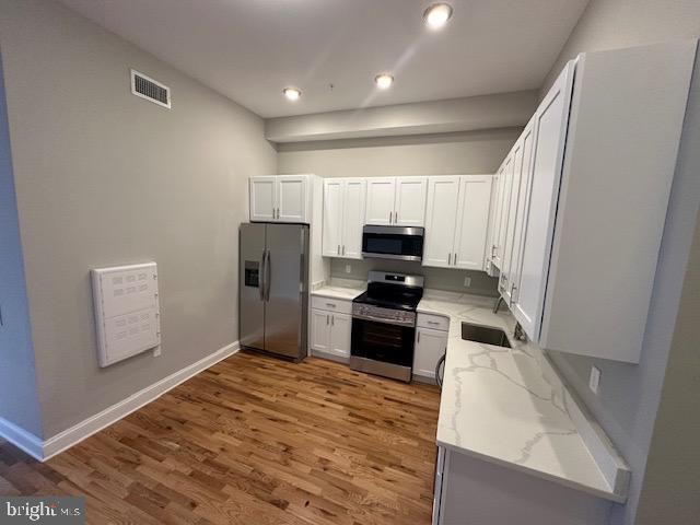 100 West Lexington Street, Unit 305 Baltimore, MD 21201 - Photo 36 of 38 a kitchen with white cabinets and stainless steel appliances