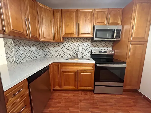a kitchen with granite countertop a stove top oven microwave and cabinets