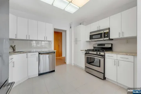 a kitchen with granite countertop white cabinets and stainless steel appliances