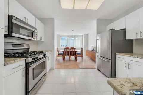 a kitchen with stainless steel appliances granite countertop a stove top oven a refrigerator and a fireplace