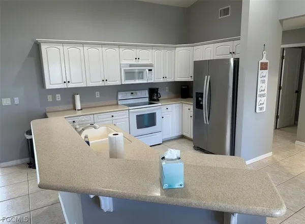 a kitchen with stainless steel appliances granite countertop a refrigerator a stove a sink and white cabinets