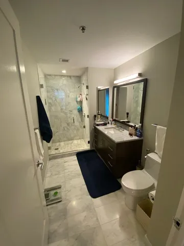 a bathroom with a sink a toilet a mirror and shower