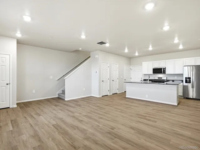 a view of kitchen with refrigerator and white cabinets