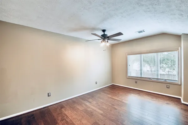 an empty room with wooden floor and windows