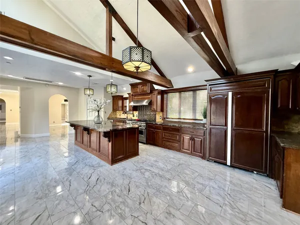 a large open kitchen with stainless steel appliances kitchen island granite countertop a refrigerator and a stove