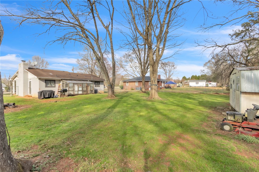 139 Louise Drive Pendleton, SC 29670 - Photo 25 of 26 Expansive outdoor space offering a lush lawn, a charming shed, and mature trees.