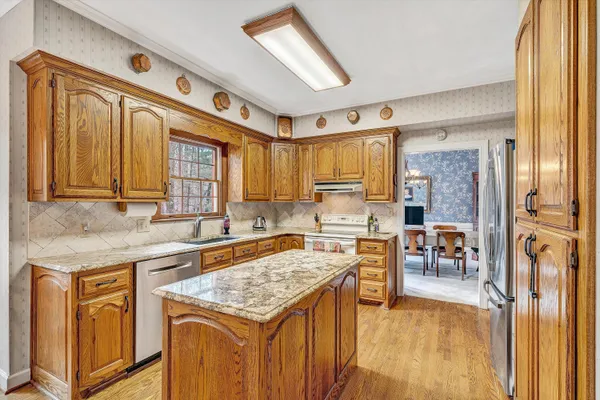 a kitchen with a stove a sink a refrigerator wooden floor and cabinets