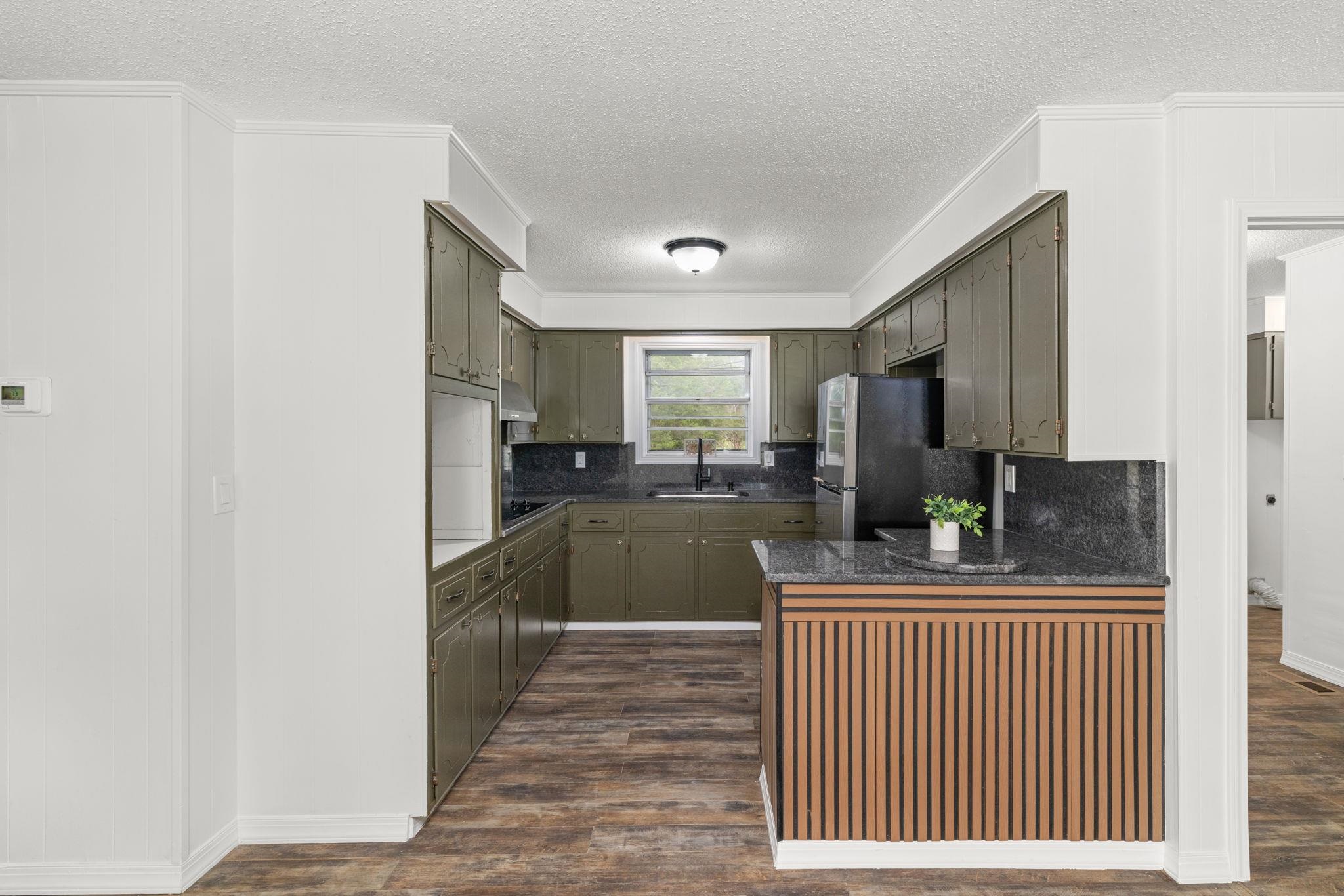 217 Red Bay Road Golden, MS 38847 - Photo 8 of 33 Kitchen featuring L-shaped dark cabinetry, black appliances, dark speckled countertops, and wood-finish flooring