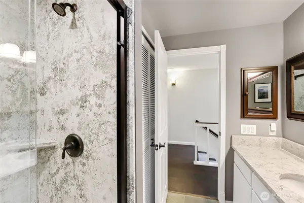 a bathroom with a granite countertop shower a mirror and a sink