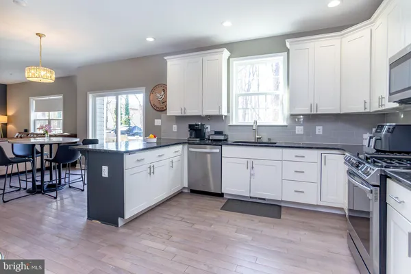 a kitchen with stainless steel appliances granite countertop white cabinets a window a sink and a stove