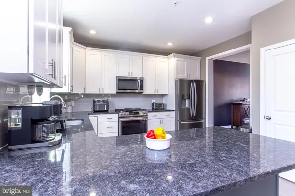 a kitchen with stainless steel appliances granite countertop a sink a stove a refrigerator a microwave a counter top space and cabinets