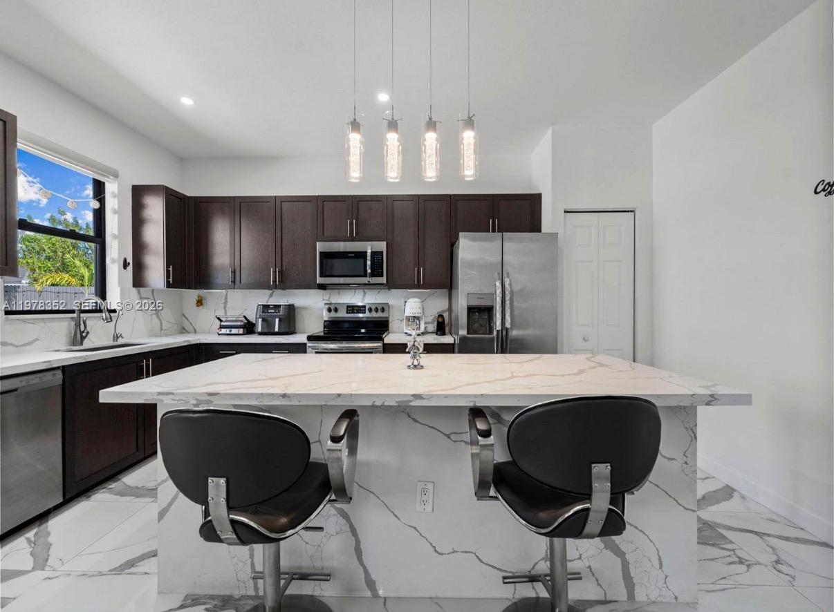 13351 Southwest 190th Street Miami, FL 33177 - Photo 12 of 45 a kitchen with kitchen island a stove a sink a microwave a dining table and chairs