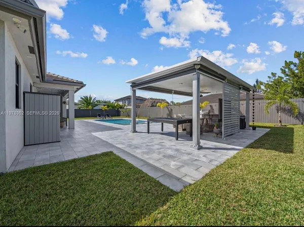 a swimming pool with outdoor seating and yard in back