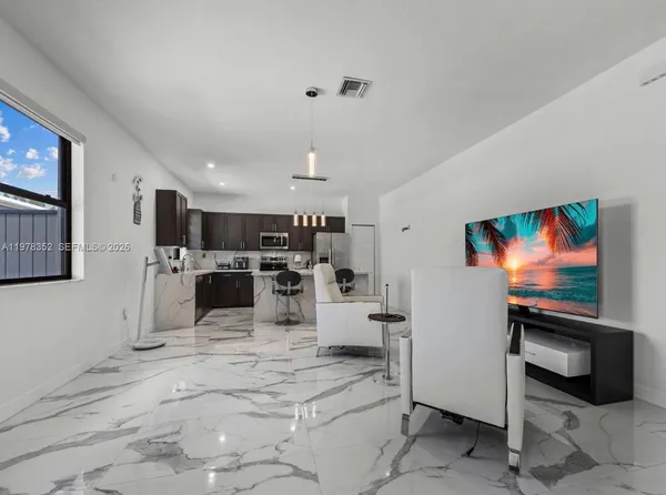 a kitchen with stainless steel appliances kitchen island a table chairs refrigerator and microwave