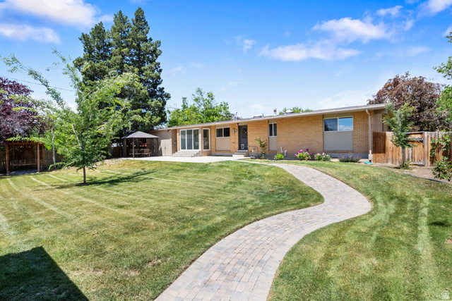 576 East 3950 North Provo, UT 84604 - Photo 42 of 47 Expansive backyard featuring a winding paver pathway, a large concrete patio, and mature trees