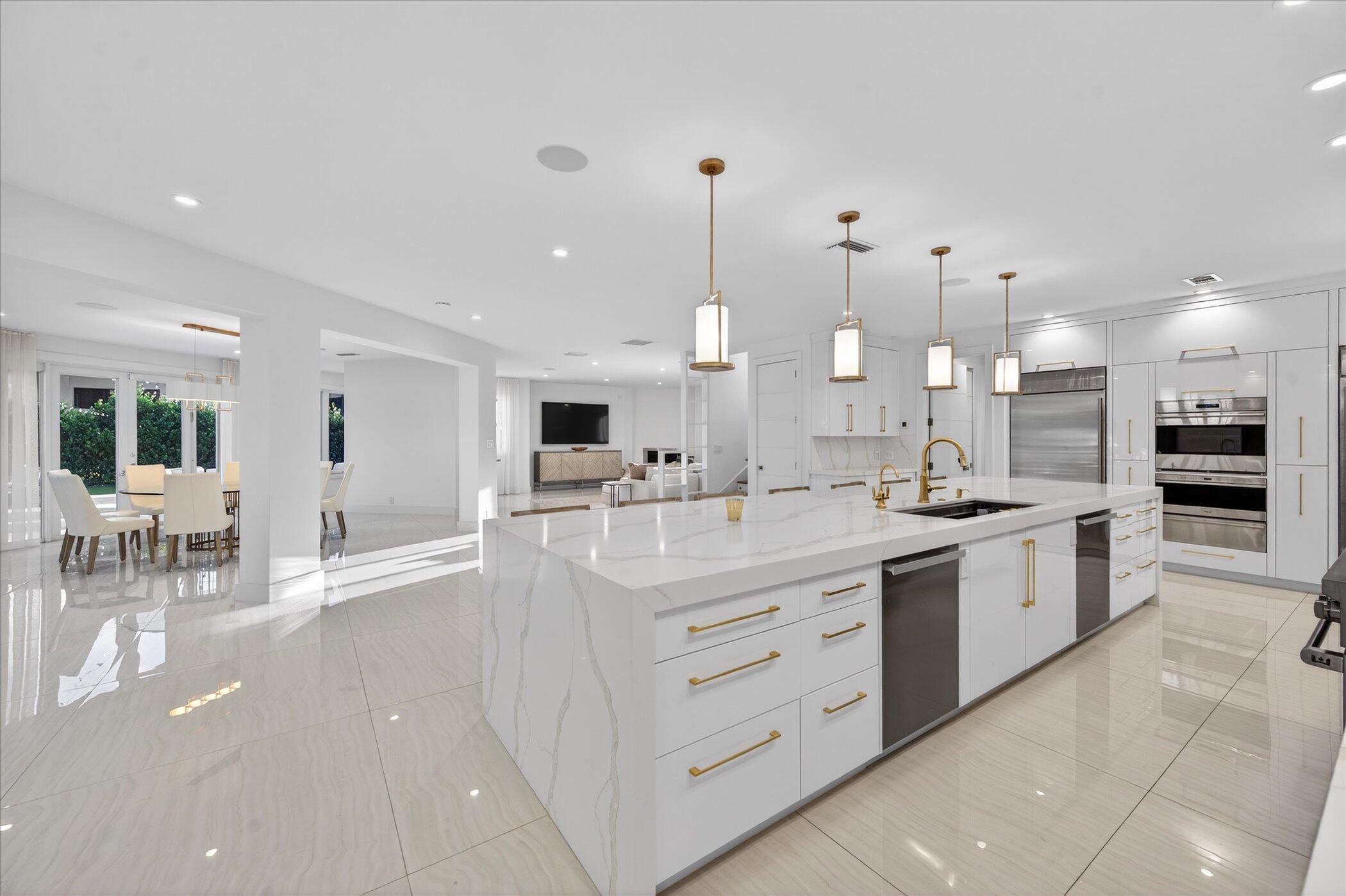 3872 Northwest 53rd Street Boca Raton, FL 33496 - Photo 10 of 43 a large white kitchen with kitchen island a sink a stove a dining table and chairs