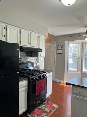 a kitchen with granite countertop stainless steel appliances a stove and wooden floor