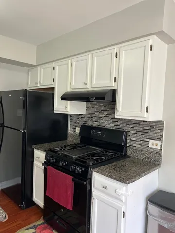 a kitchen with granite countertop a stove top oven and cabinets