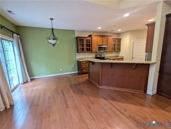 a view of kitchen with stainless steel appliances granite countertop cabinets and wooden floor