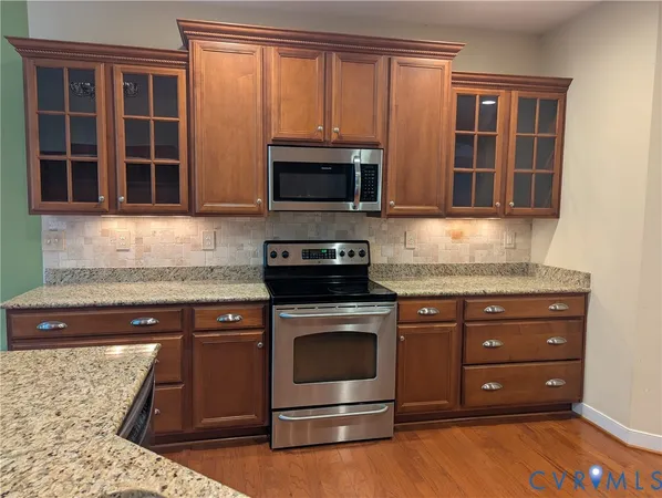 a kitchen with granite countertop wooden cabinets stainless steel appliances and a counter space