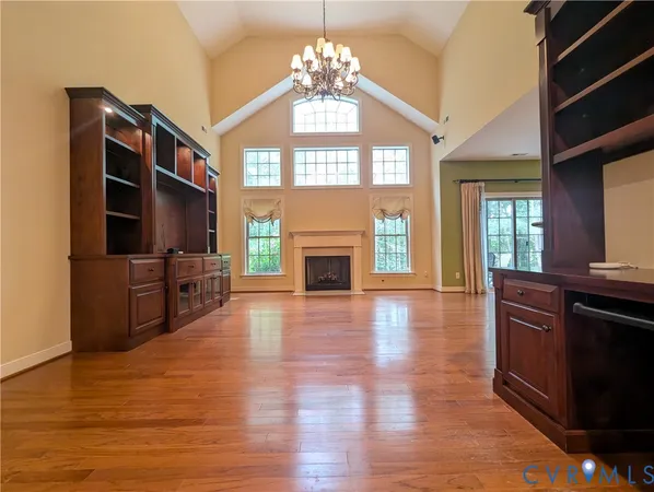 a view of an empty room with wooden floor fireplace and a window