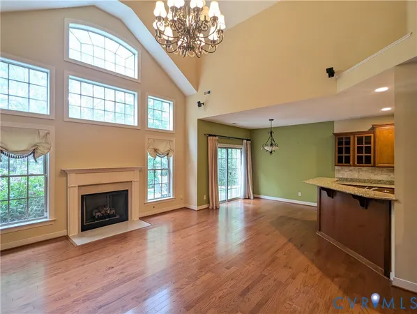 an empty room with wooden floor fireplace and windows