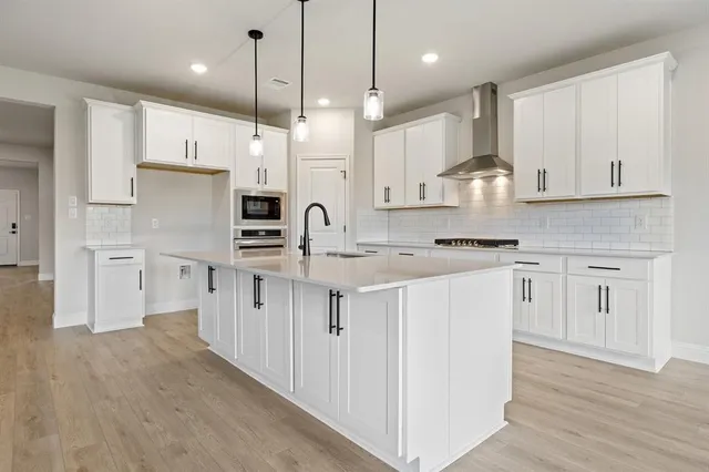 a kitchen with stainless steel appliances a stove a sink and white cabinets