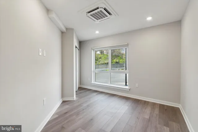 an empty room with wooden floor and windows