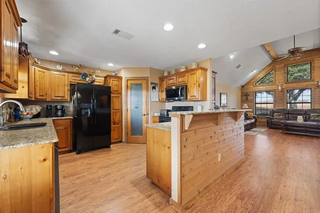 a kitchen with a refrigerator a stove top oven a sink dishwasher and wooden cabinets with wooden floor