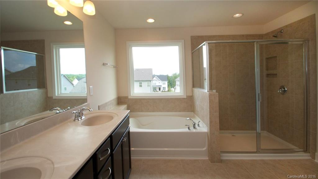 5706 Joshua Cain Road, Unit L0041 Charlotte, NC 28213 - Photo 20 of 23 a bathroom with a granite countertop sink a mirror and a bathtub