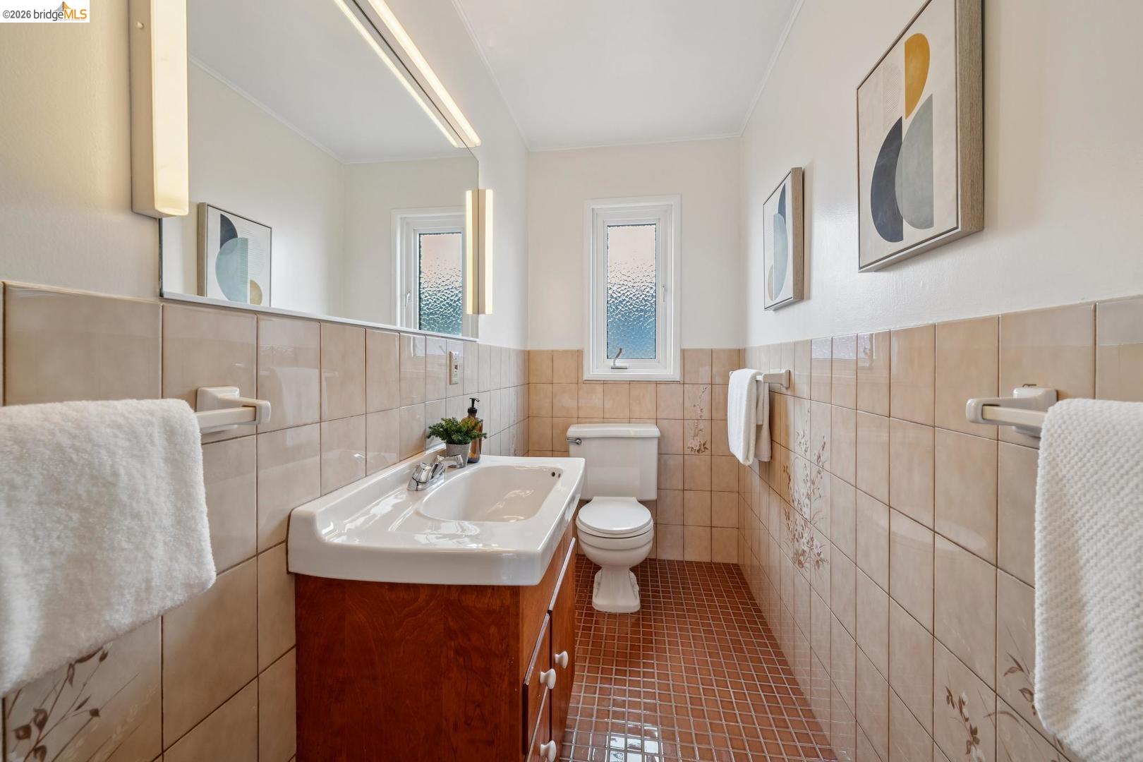 155 Avenida Drive Berkeley, CA 94708 - Photo 29 of 86 White ceramic toilet, window with textured glass, wood-finish vanity with an integrated sink, wall-mounted mirror, and ceramic wall tiling