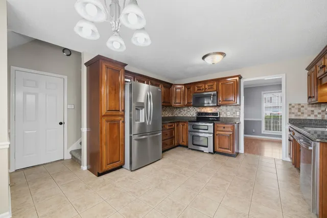 a large kitchen with stainless steel appliances granite countertop a refrigerator and a stove top oven