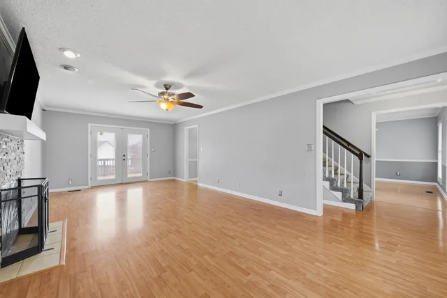 a view of an empty room with window and wooden floor