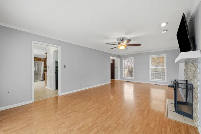 a view of empty room with wooden floor and fan