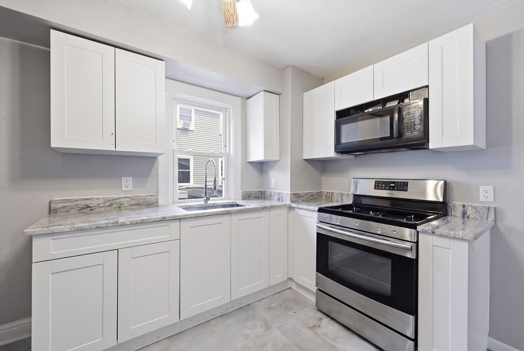 62 Kenyon Street Springfield, MA 01109 - Photo 12 of 26 a kitchen with stainless steel appliances granite countertop grey cabinets a stove a sink and dishwasher