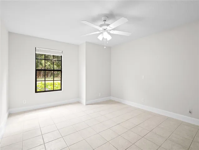 a view of an empty room with chandelier fan and fire place
