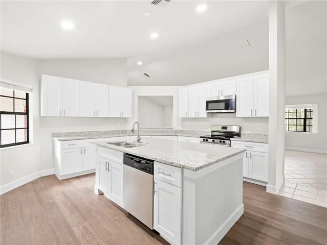 a kitchen with white cabinets appliances and sink