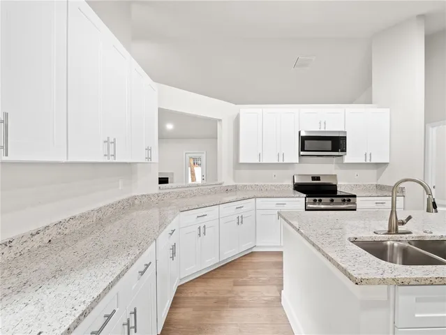 a kitchen with granite countertop a sink and white cabinets