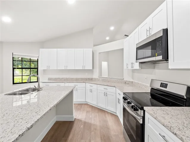 a kitchen with stainless steel appliances granite countertop a sink dishwasher stove and microwave with wooden cabinets