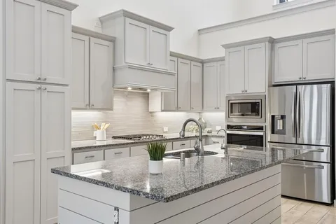a kitchen with kitchen island granite countertop a sink stove and refrigerator
