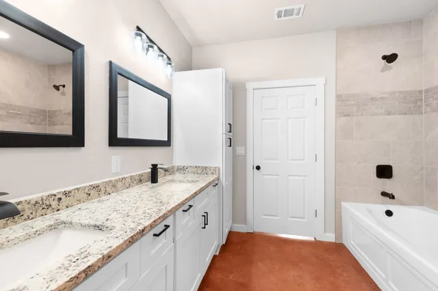 a bathroom with a granite countertop tub sink and mirror