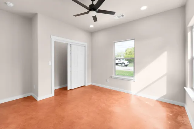 an empty room with windows and fan