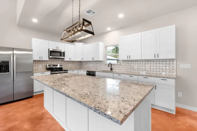 a kitchen with stainless steel appliances granite countertop a sink a stove and a refrigerator