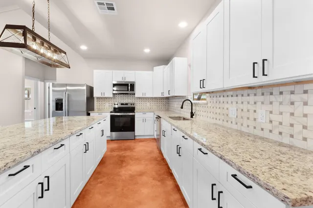 a large kitchen with granite countertop a sink and cabinets