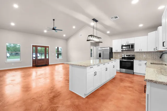 a large kitchen with stainless steel appliances granite countertop a lot of counter space and wooden floor