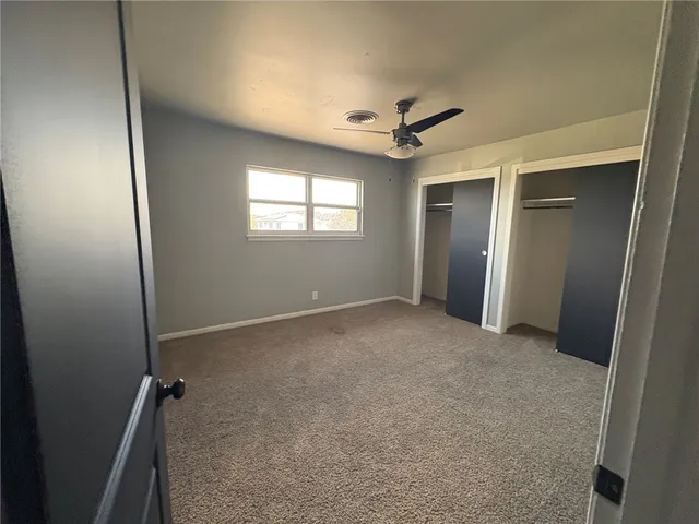 an empty room with windows and a ceiling fan
